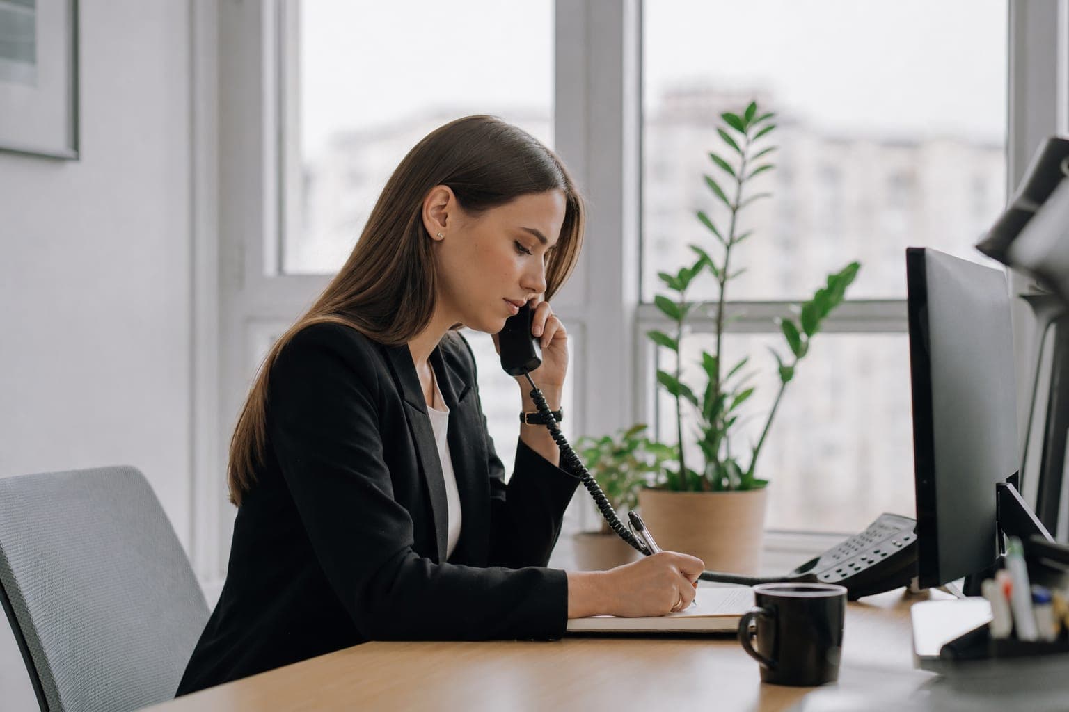 Recruiterin im Telefonat mit Notizblock am Schreibtisch